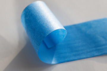Curled blue painter's tape close-up  
A detailed close-up of blue painter's tape curling off the roll. Used for masking, painting, and surface protection in DIY projects.  
