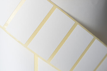 Close-up of blank adhesive label stickers roll. A detailed close-up of a roll of blank adhesive label stickers with rectangular shapes, commonly used for printing, packaging, and organization.  

