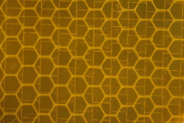 Close-up of yellow reflective tape hexagonal pattern  
A macro close-up of yellow reflective tape...