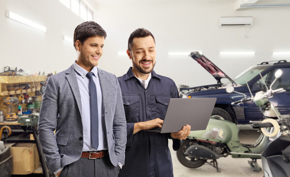 Auto mechanic with a client standing in a car garage
