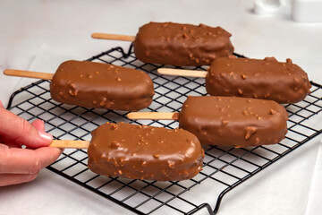 Woman’s Hand Placing Chocolate-Dipped Ice Cream Bars on Rack