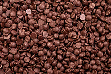 Dark Chocolate Drops Top View.A top-down view of dark chocolate callets (drops) scattered on a neutral background