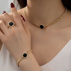 A woman wearing a gold-toned jewelry set. The set consists of a choker necklace, ring, and...