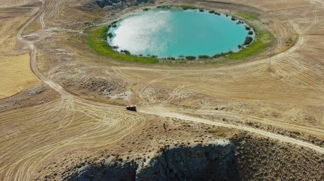 The surroundings of Ağ Lake and Kara Lake, the drone zooms out over a red vehicle and two young people standing among golden yellow fields and dirt roads.