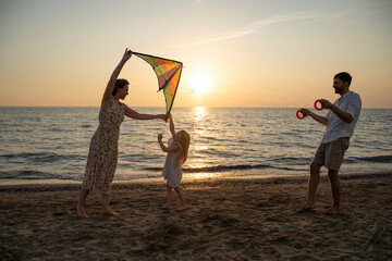 Family enjoying a sunset kite flying on Italian beach