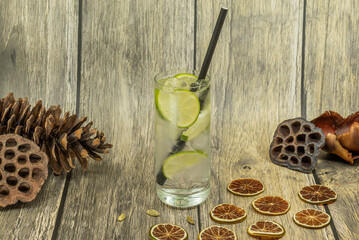 Lime cocktail with ice and dried citrus slices on rustic wooden background
