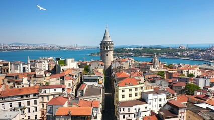 A stunning aerial view of Istanbul. Iconic Galata Tower, vibrant buildings, and the sparkling Golden Horn on a bright, sunny day. Old city in the distance