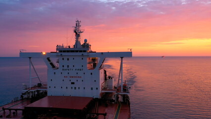 Bulk carrier loaded with grains underway under a crimson sky. Merchant ship Fakarava designed to...