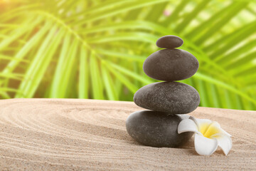 Stack of zen stones with white flower on sand. Harmony with nature concept