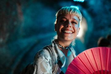 Obraz premium Young woman smiling and holding folding fan at festival