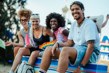 Happy friends enjoying music festival with colorful hand fans