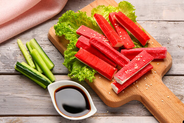 Board with tasty crab sticks and sauce on light wooden background © Pixel-Shot