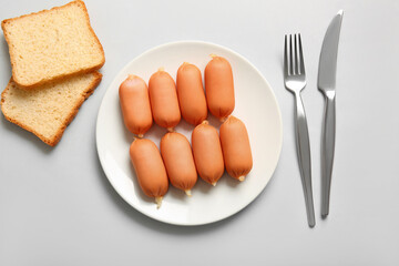 Plate of tasty boiled sausages on grey background