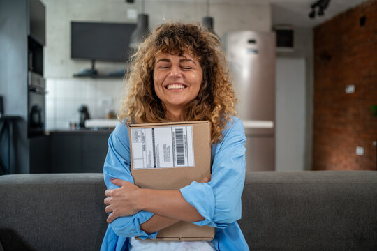 Happy woman hugging a package at home