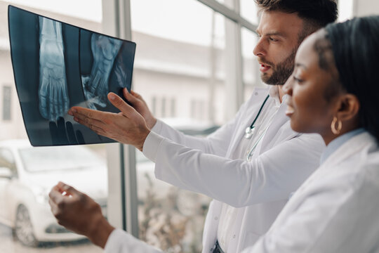 Doctors examining x ray of foot in hospital room - Powered by Adobe