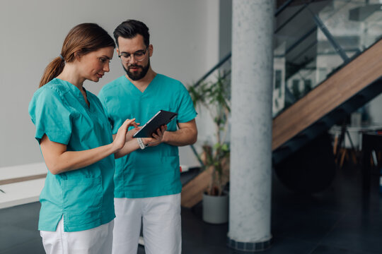 Two healthcare professionals using digital tablet in modern clinic