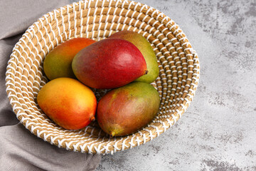 Bowl of fresh ripe mangoes on grunge background