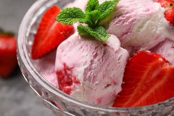 Bowl of strawberry ice cream with berries and mint on table, closeup