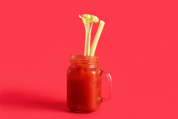 Mason jar of bloody mary with celery on red background