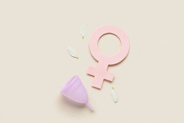 Composition with menstrual cup and woman symbol made of paper on beige background