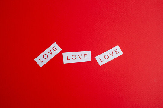 Paper with the word "love" written in red font on a red background. Love theme. Love message. Romantic love note on paper. Space for text
