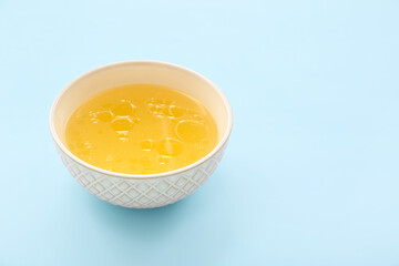 Bowl of tasty vegetable broth on blue background