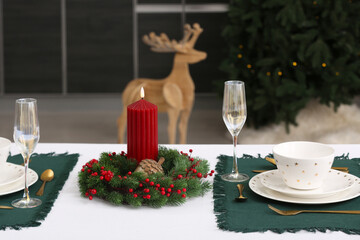 Table setting with Christmas wreath and burning candle in kitchen, closeup