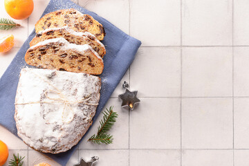 Composition with tasty Christmas stollen on white tile background