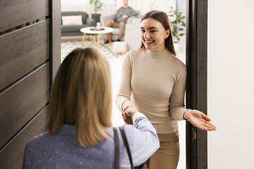 Happy woman greeting neighbor and welcoming her to apartment