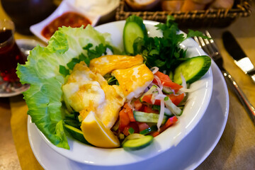 Hellim salata, turkish salad with cheese, tomato, cucumber, onion and lemon in a restaurant