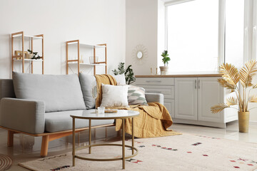 Interior of light living room with golden decor and sofa