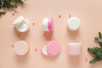 Jars of cream with Christmas decorations on pale orange background
