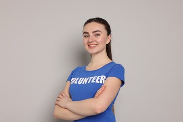 Portrait of smiling volunteer with crossed arms on grey background