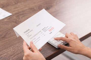 Fototapeta premium Paying bills. Woman with different invoices and calculator at wooden table indoors