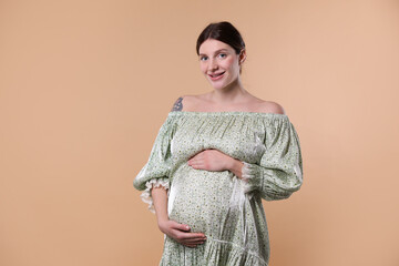 Beautiful pregnant woman with cute belly on beige background