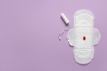 Menstrual pad with paper blood drop and tampon on purple background