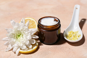 Composition with jar of cosmetic product, lemon and flower on color background