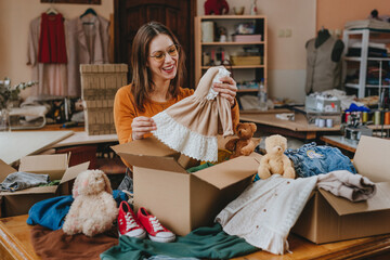 Woman sorting an old out-of-use kid toy, clothes and shoes in box for charity or upcycling