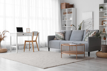 Interior of living room with cozy grey sofa and wooden coffee table