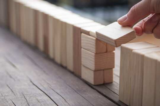 Closeup hand that building the wooden pieces as a bridge, and going to fill the gap with the last piece, gap and disconnect problem, solution to solve it, build success
