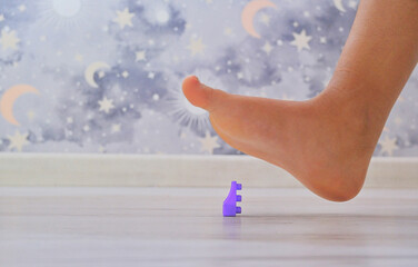 A foot hovers over toy building blocks, conveying pain and capturing the essence of life with young children.