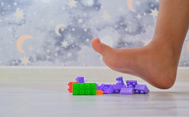 A foot hovers over toy building blocks, conveying pain and capturing the essence of life with young...