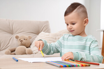 Little boy drawing with felt-tip pens on table at home