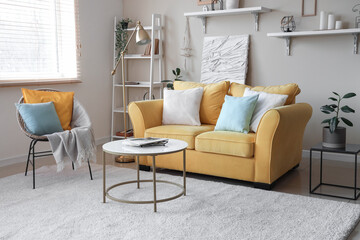 Stylish living room with yellow sofa, carpet, armchair, carpet and coffee table