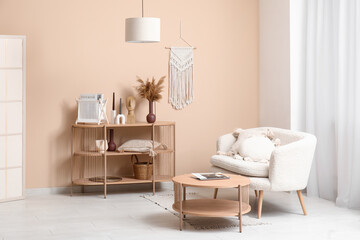 Comfortable sofa and shelving unit with different decor near beige wall in interior of modern living room