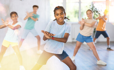 Happy boys and girls enjoying active dance in studio
