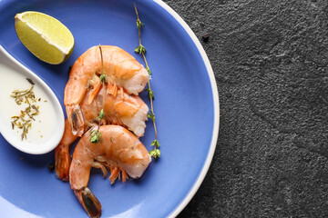 Plate with tasty boiled shrimps, lime and spoon of sauce on dark background