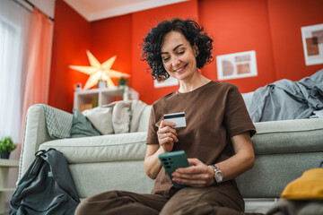 woman sit on floor near suitcase and have online shopping on cellphone