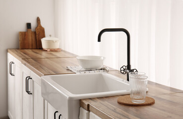 Sink on wooden counter near window in stylish kitchen