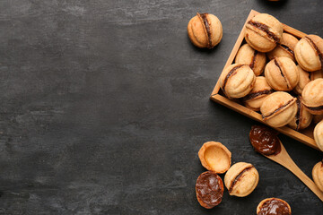 Wooden box with sweet walnut shaped cookies with boiled condensed milk on black background